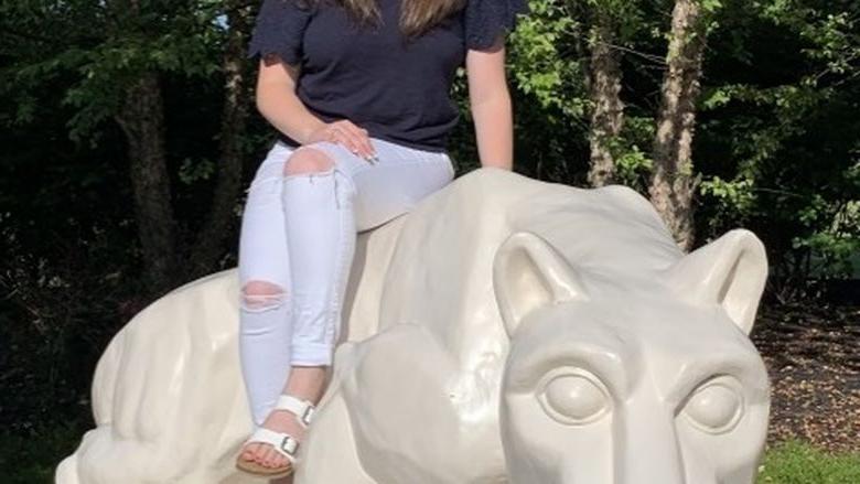 学生坐在宾州立大学狮子雕像上
