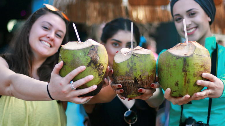 三个年轻的女人拿着椰子饮料